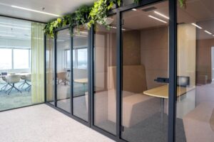Modern office space at Amstelplein with glass-walled meeting rooms, indoor plants, and contemporary furniture.