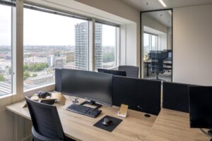 Modern office workspace at Amstelplein with city view through large windows.
