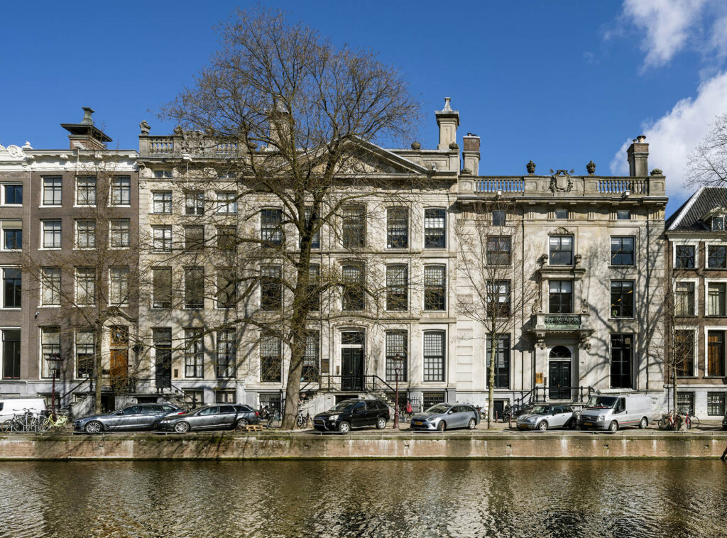 Monumentale grachtenpanden aan de Herengracht in Amsterdam, gezien vanaf de overkant van de gracht op een zonnige dag.