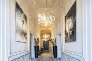 Luxe hal aan de Herengracht met kroonluchters, moderne kunstwerken en marmeren lambrisering.