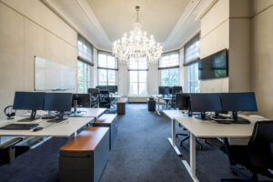 Modern kantoor aan de Herengracht met open werkplekken, grote ramen en een opvallende kroonluchter.