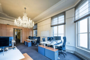 Licht en klassiek ingericht kantoor aan de Herengracht met moderne werkplekken en een grote kristallen kroonluchter.