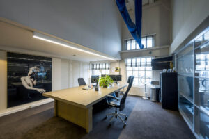 Modern kantoorinterieur aan de Herengracht met een groot bureau, strak meubilair en kunst aan de muur.