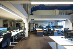 Modern kantoorinterieur aan de Herengracht met meerdere werkplekken, bureaustoelen en computerschermen.
