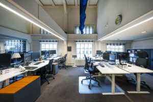 Modern kantoorinterieur aan de Herengracht met meerdere bureaus, computers en ergonomische bureaustoelen.