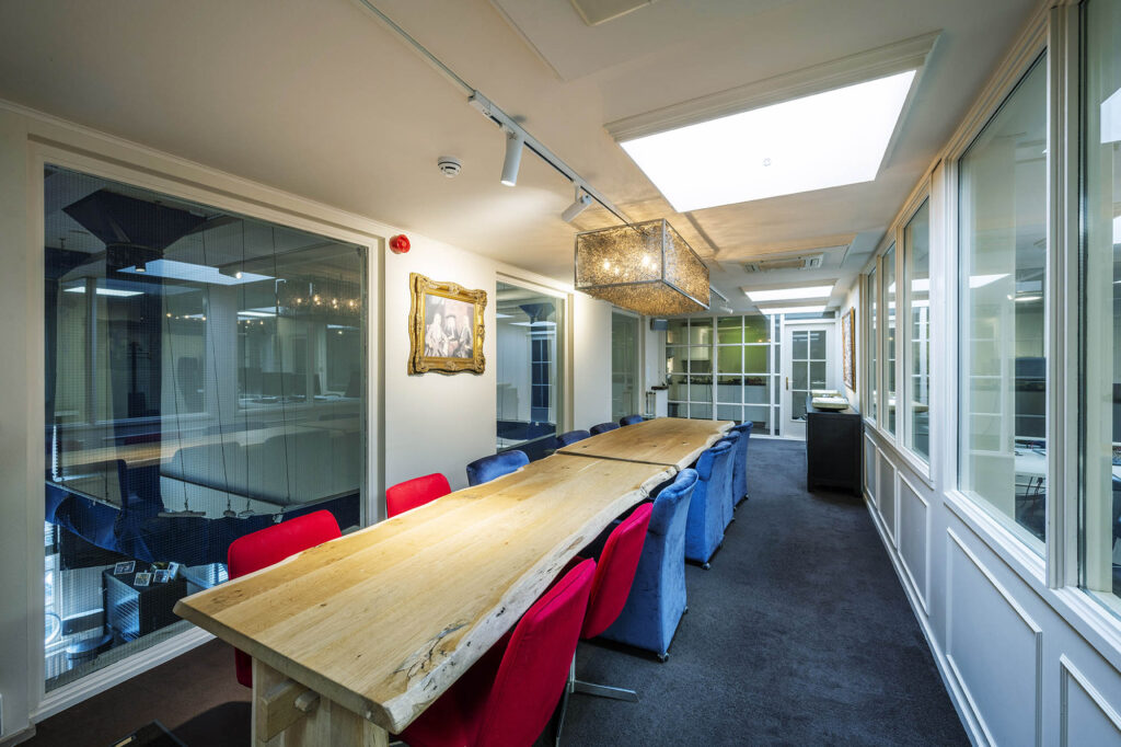 Vergaderruimte met een lange houten tafel, kleurrijke stoelen en moderne verlichting aan de Herengracht.