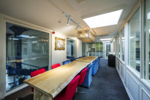 Vergaderruimte met een lange houten tafel, kleurrijke stoelen en moderne verlichting aan de Herengracht.