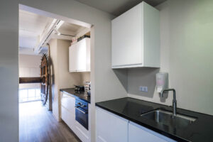 Moderne kitchenette met witte kasten, zwarte werkbladen en ingebouwde apparatuur aan de Herengracht.