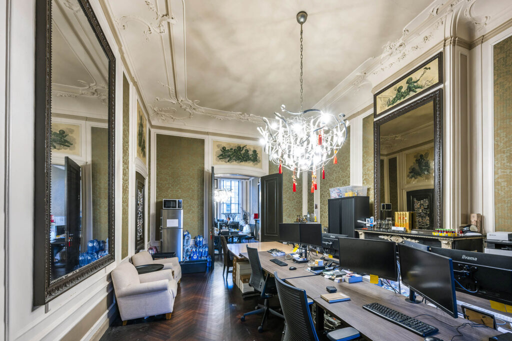 Klassiek ingerichte kantoorruimte aan de Herengracht met sierplafond, grote spiegels en moderne werkplekken.