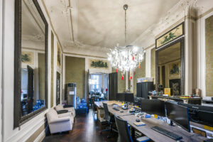 Klassiek ingerichte kantoorruimte aan de Herengracht met sierplafond, grote spiegels en moderne werkplekken.