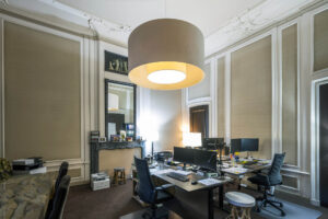 Modern kantoorinterieur aan de Herengracht met klassieke elementen, werkplekken en een grote hanglamp.