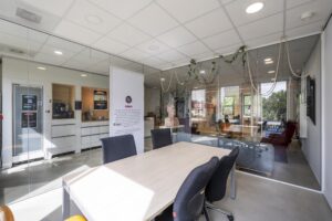 Vergaderruimte met glazen wanden, ingericht met een tafel, zwarte stoelen en uitzicht op een moderne kantoorruimte aan de Naritaweg.