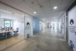 Moderne kantoorgang op Naritaweg met glazen wanden, inspirerende citaten op de deuren en zicht op werkplekken.