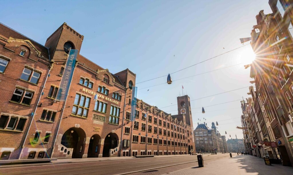 Zicht op de Beurs van Berlage aan het Damrak in Amsterdam op een zonnige dag.