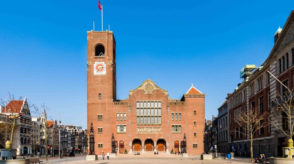 The Beurs van Berlage building on Damrak in Amsterdam under a clear blue sky.
