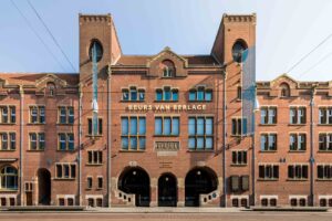 Vooraanzicht van de Beurs van Berlage aan het Damrak in Amsterdam, met symmetrische baksteenarchitectuur en twee torens.