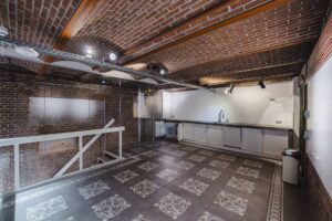 Moderne keuken met wit tegelwerk en kastjes, gelegen in een ruimte met bakstenen muren en plafond aan het Damrak.