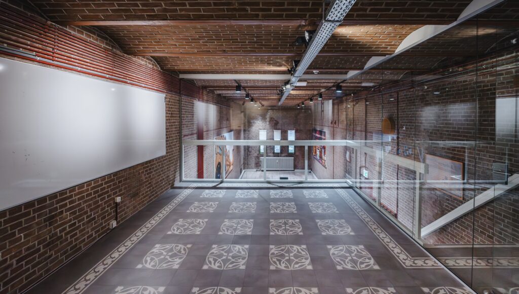 Interior view of a modern hallway at Damrak 217 with brick walls, patterned floor tiles, and glass railings.