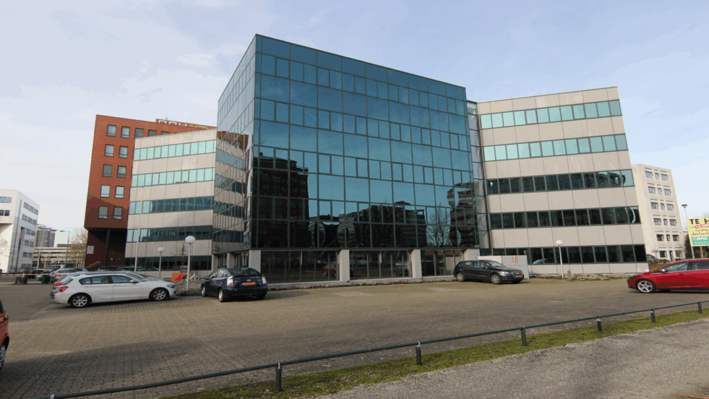 Kantoorpand aan de Hogehilweg 18 in Amsterdam met spiegelende gevel en parkeergelegenheid ervoor.