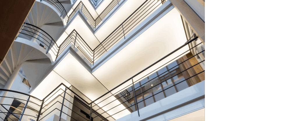 Binnenkant van het kantoorgebouw aan de Hogehilweg met zigzaggende balustrades en een moderne wenteltrap.