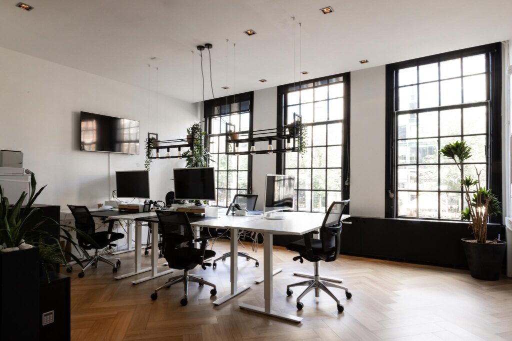 Modern kantoorinterieur op de Rokin met werkplekken, grote ramen en veel natuurlijk licht.