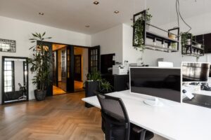 Modern en licht kantoorinterieur aan het Rokin met bureauopstellingen, planten en industriële verlichting.