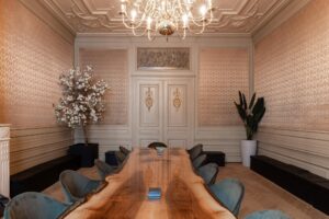 Luxe vergaderruimte aan het Rokin met een houten boomstamtafel, fluwelen stoelen, kroonluchter en klassieke wand- en plafonddecoratie.