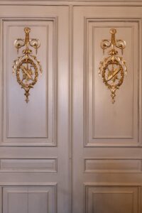 Houten paneeldeuren met gouden, symmetrische ornamentversiering in een klassiek interieur aan het Rokin.