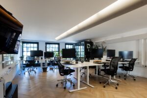 Moderne kantoorruimte aan het Rokin met meerdere werkplekken, grote schermen en natuurlijk licht.