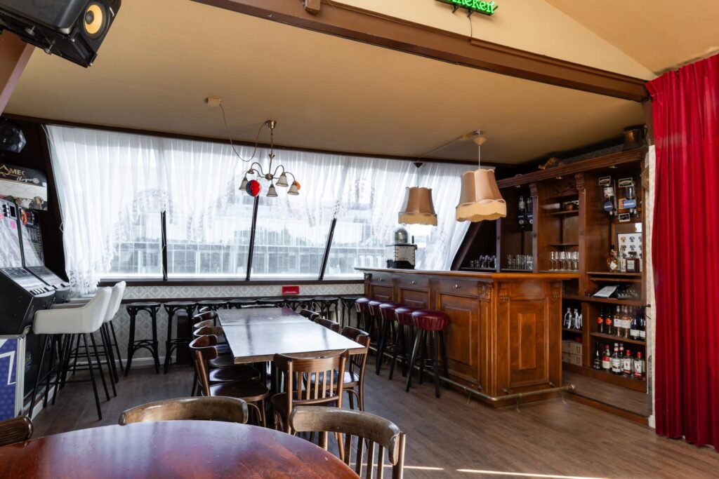 Knusse bar met houten interieur, barkrukken en speelkast aan het Rokin in Amsterdam.
