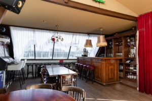 Knusse bar met houten interieur, barkrukken en speelkast aan het Rokin in Amsterdam.
