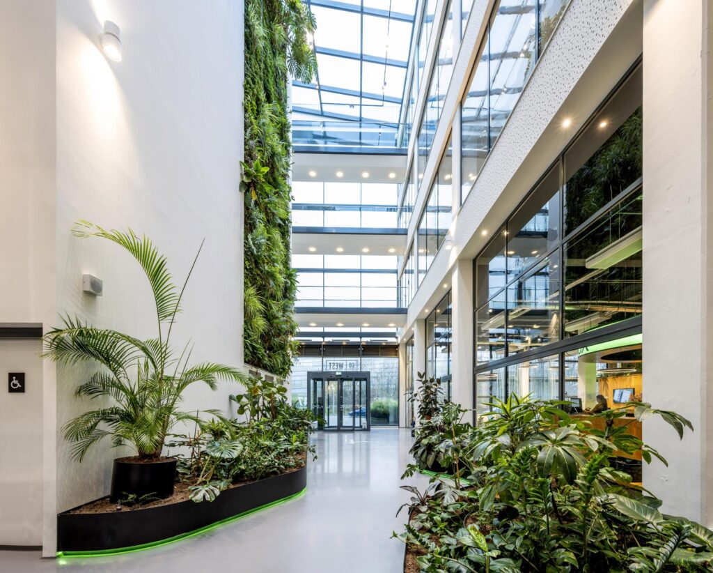 Moderne en lichte kantoorentree aan de Kabelweg met veel groen en een verticale plantenwand.
