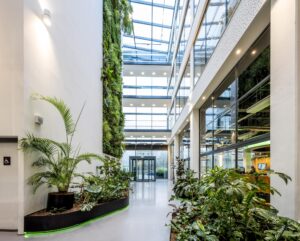 Moderne en lichte kantoorentree aan de Kabelweg met veel groen en een verticale plantenwand.
