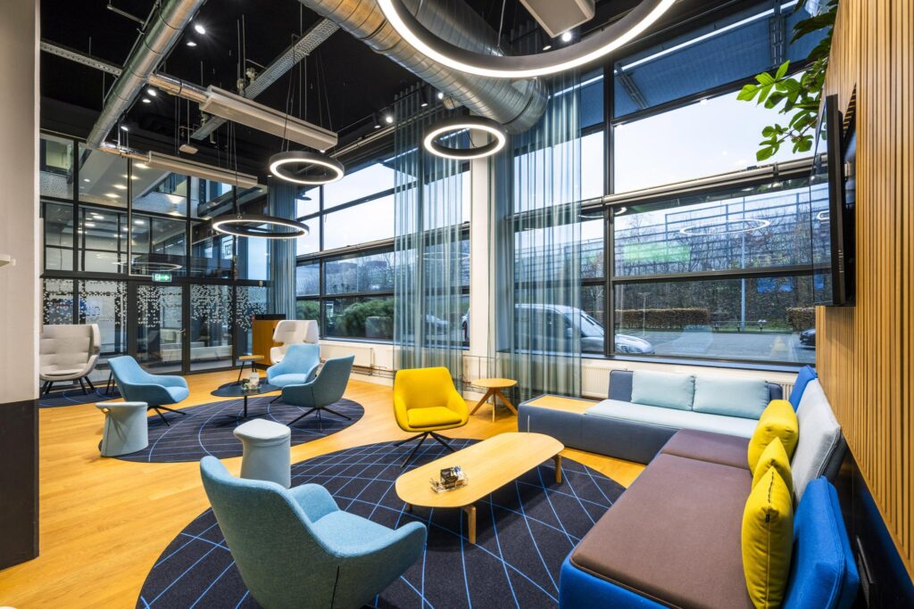 Moderne wachtruimte met kleurrijke stoelen, grote ramen en industriële plafondverlichting aan de Kabelweg.