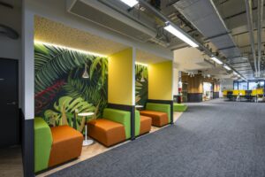 Moderne kantoorruimte aan de Kabelweg met kleurrijke zitnissen, tropisch behang en open werkplekken.