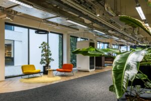 Moderne kantoorruimte aan de Kabelweg met kleurrijke zitjes, veel groen en een akoestische belcel.