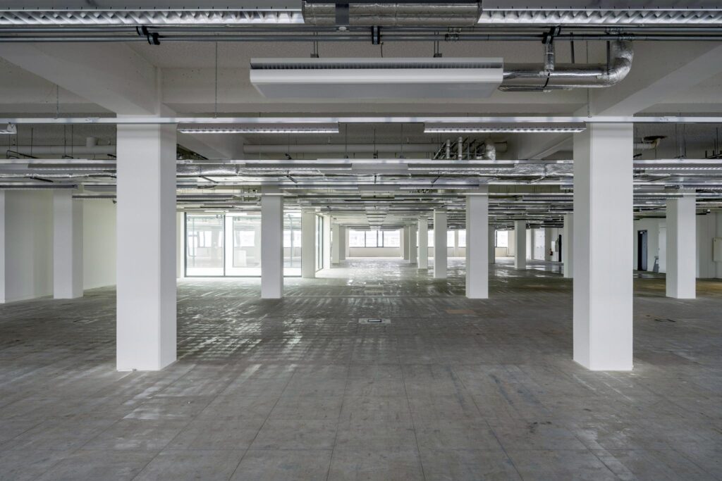 Leegstaand kantoorpand aan de Kabelweg met betonnen vloer en zichtbare plafonleiding.