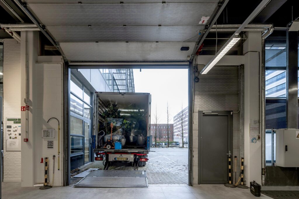 Een vrachtwagen met planten wordt uitgeladen bij een laadperron aan de Kabelweg.