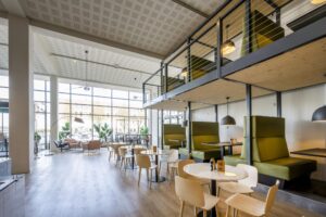 Moderne en lichte bedrijfsruimte aan de Kabelweg met hoge ramen, open zitplekken en groene zithoeken.