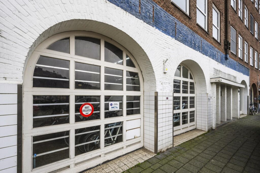 White arched garage doors with a "No entry" sign on Baarsjesweg in Amsterdam.