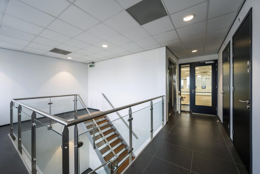 Moderne trapopgang en gang met glazen balustrade in een kantoorpand aan de Sijsjesbergweg.