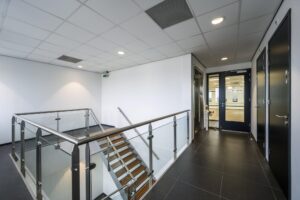 Moderne trapopgang en gang met glazen balustrade in een kantoorpand aan de Sijsjesbergweg.
