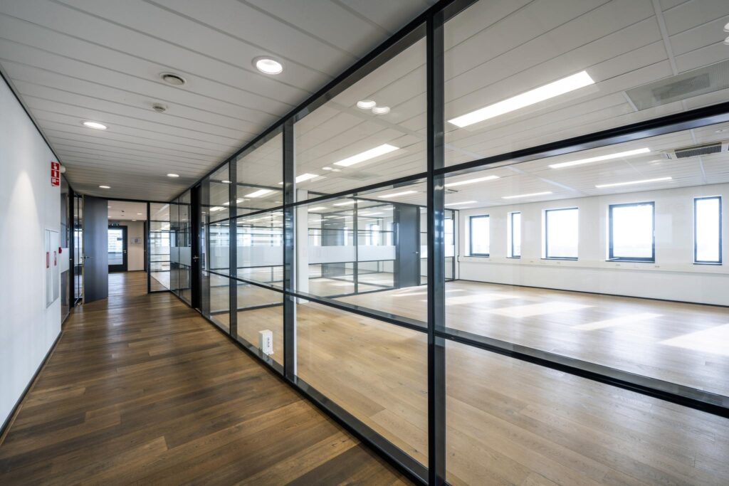 Moderne, lichte kantoorruimte aan de Sijsjesbergweg met glazen wanden en houten vloer.
