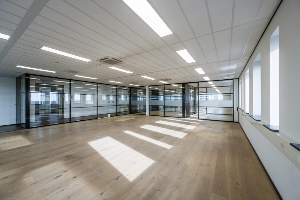 Lichte, moderne kantoorruimte aan de Sijsjesbergweg met glazen wanden en houten vloer.