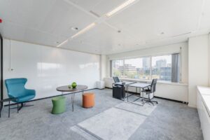 Lichte moderne kantoorruimte aan de Laarderhoogtweg met bureau, zithoek en uitzicht op omliggende gebouwen.