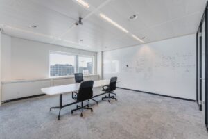 Lichte vergaderruimte aan de Laarderhoogtweg met glazen whiteboardwand en uitzicht op moderne kantoorgebouwen.