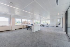 Ruime en lichte kantoorruimte aan de Laarderhoogtweg met grote ramen en enkele bureaus.