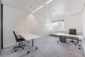 Lichte, moderne kantoorruimte aan de Laarderhoogtweg met twee bureaus en uitzicht op kantoorgebouwen.
