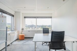 Modern kantoor met twee bureaus, uitzicht op Laarderhoogtweg en een whiteboard links.