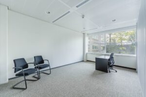 Lichte, moderne kantoorruimte aan de Laarderhoogtweg met een bureau, bureaustoel en twee bezoekersstoelen.